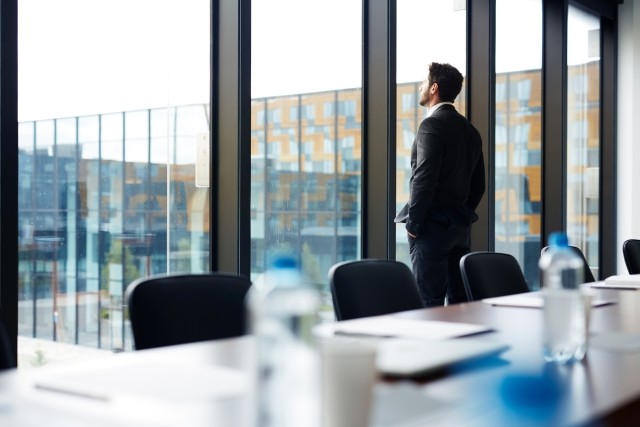 Businessman standing at window in empty board room